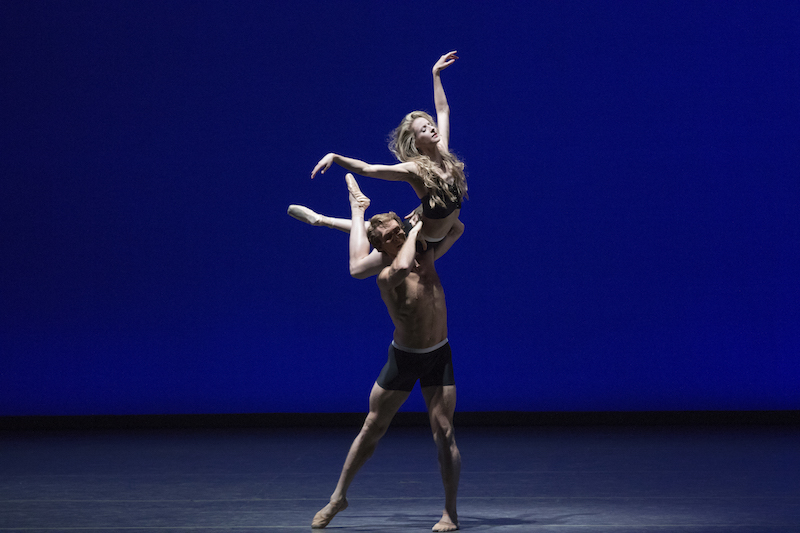 Adrian Danchig-Waring holds Sterling Hyltin on his shoulder. Both dancers wear athletic briefts and Sterling wears a black midriff top.